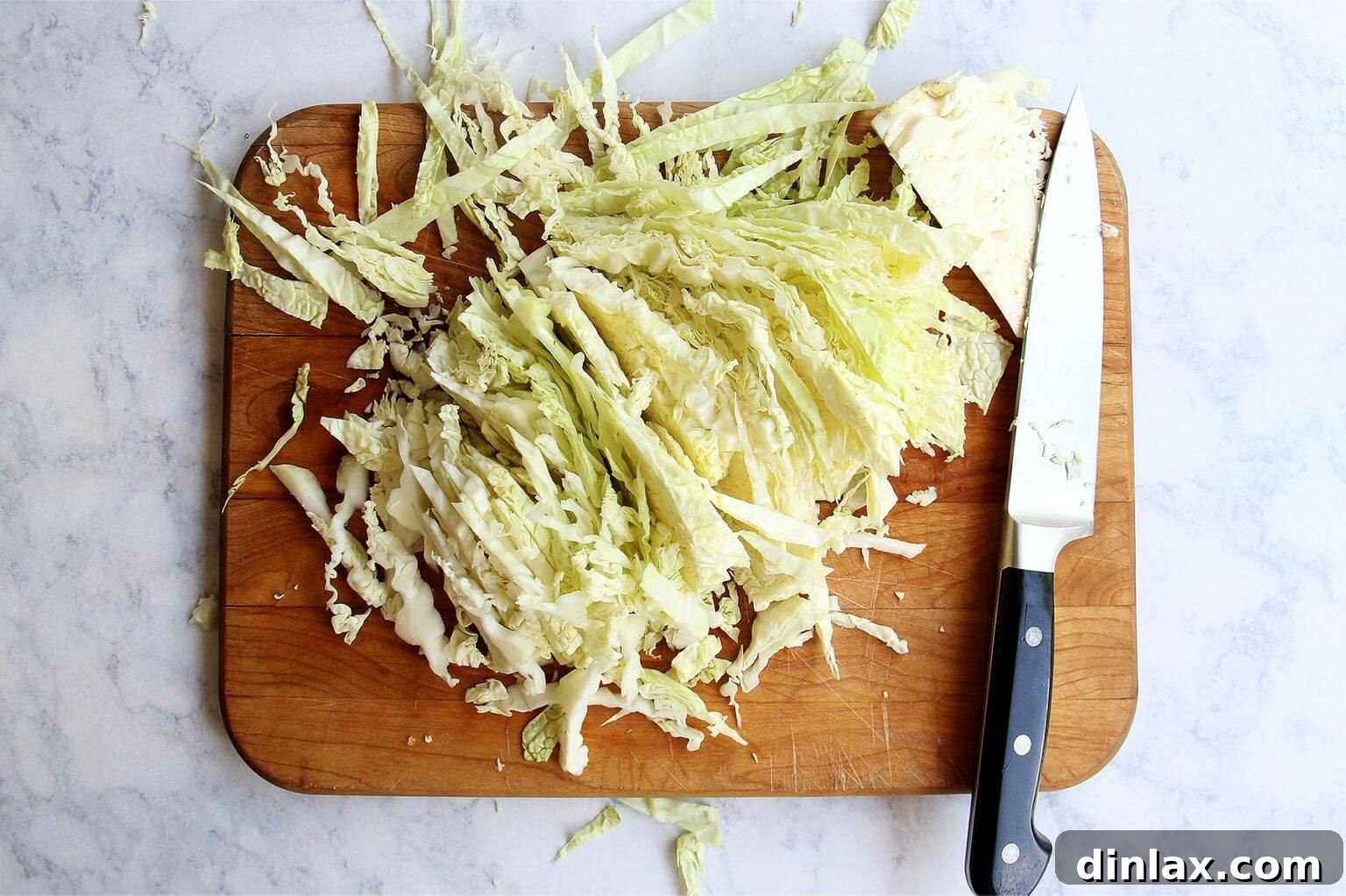 Finely shredded green cabbage on a cutting board, prepared for massaging.