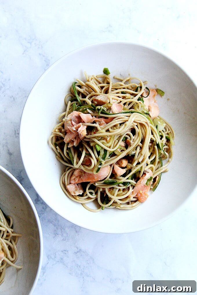 One sauce, two roles—a revelation! With dinner prep (and clean up) decreased by half, this recipe for ginger-sesame soba noodles with cedar plank salmon slips into weeknight-friendly territory, requiring about 30 minutes of work. // alexandracooks.com A bowl of cedar-planked salmon with soba noodles, garnished with fresh herbs and sesame seeds.
