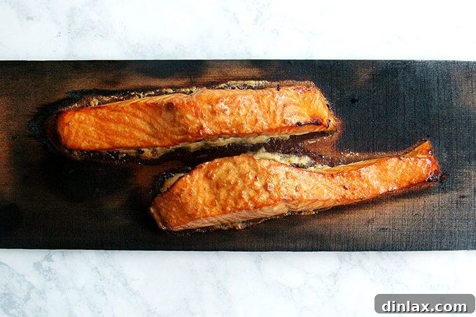 Smoky Cedar Salmon over Ginger Sesame Noodles 3 A cedar plank with perfectly grilled salmon fillets, showcasing the flaky texture and golden-brown crust.