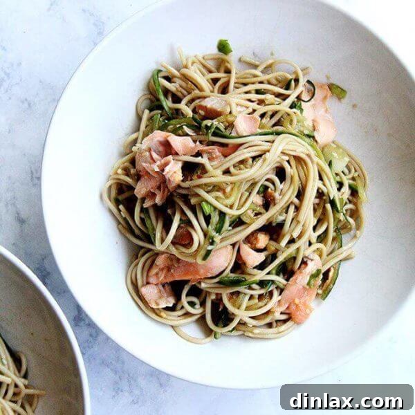 Grilled cedar-planked salmon with soba noodles, garnished with fresh herbs and sesame seeds.