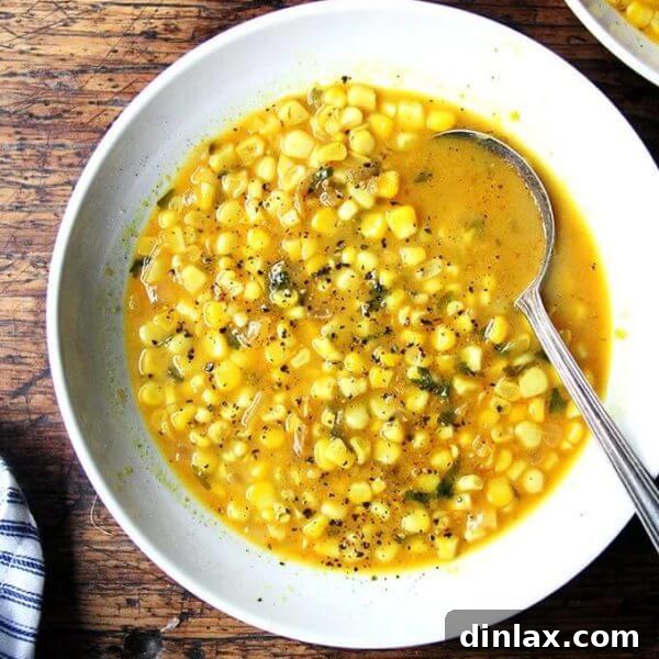 A bowl of curried coconut corn soup, garnished with fresh cilantro and a lime wedge.