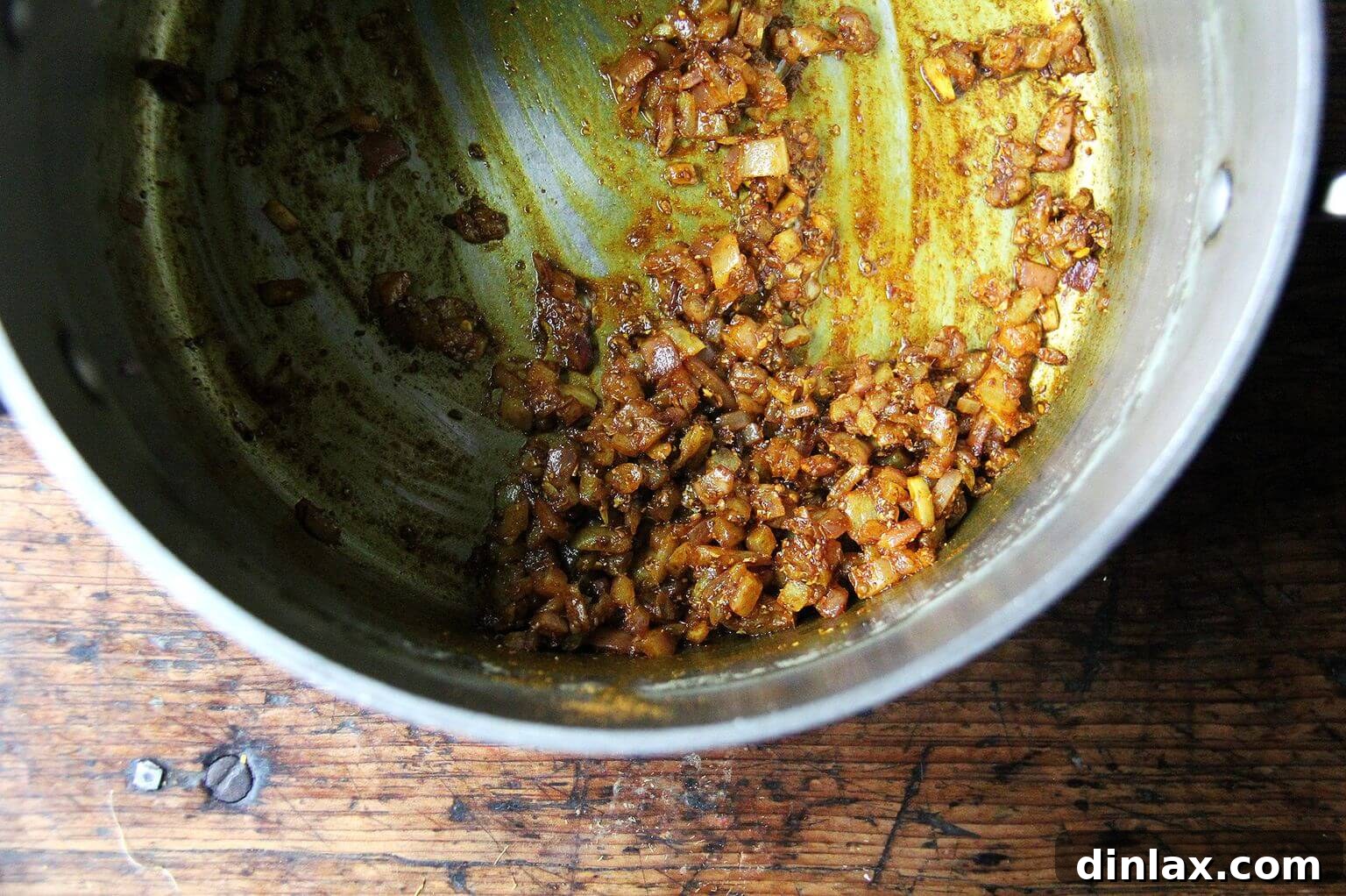 Deborah Madison's Creamy Curried Coconut Corn Soup 7 A close-up of a pot on the stovetop, where aromatic onions and curry spices are gently sautéing, filling the kitchen with a rich fragrance.