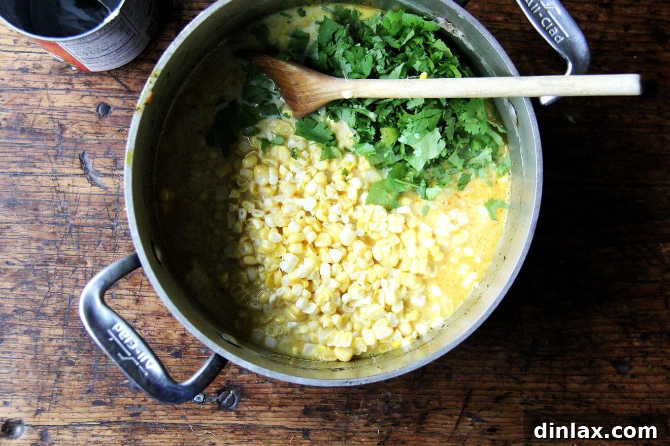 Deborah Madison's Creamy Curried Coconut Corn Soup 8 A large pot on the stove, brimming with vibrant curried corn soup, garnished with fresh cilantro leaves.
