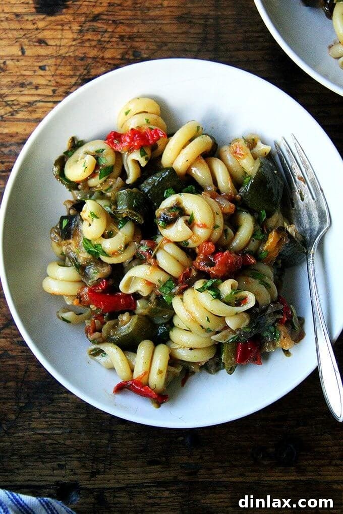 A plate of perfectly tossed pasta with roasted ratatouille, garnished with fresh basil, ready to be enjoyed as a delightful summer meal.