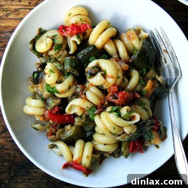 A bowl of roasted ratatouille pasta, richly coated in the vibrant vegetable sauce and garnished with fresh herbs, ready for a delicious meal.