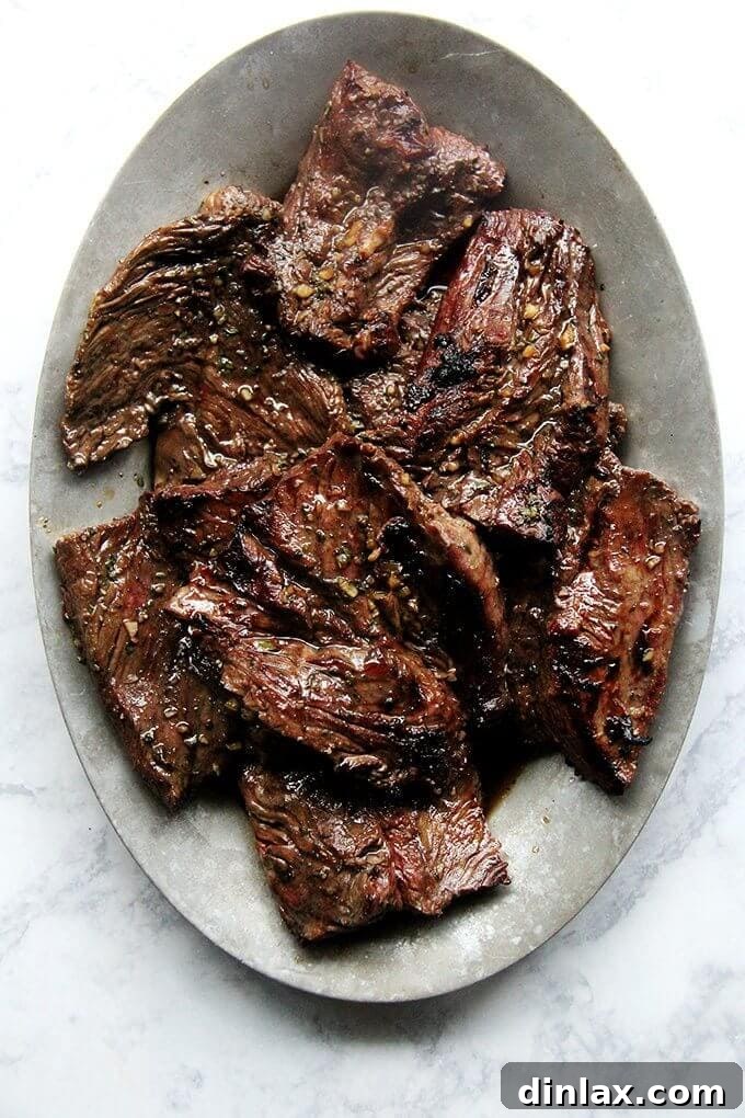 A platter of perfectly grilled hanger steak, sliced against the grain and ready to serve.