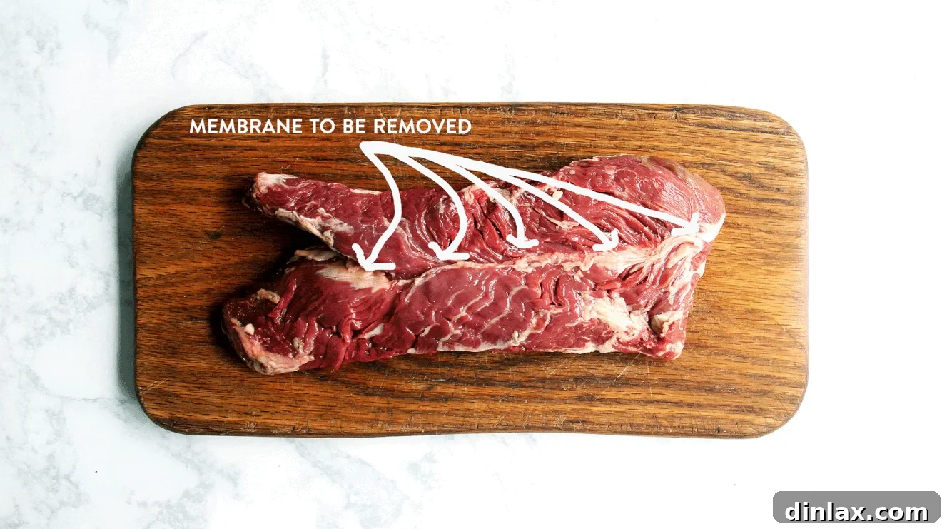 A raw hanger steak showing the thick, central membrane before trimming, crucial for proper preparation.