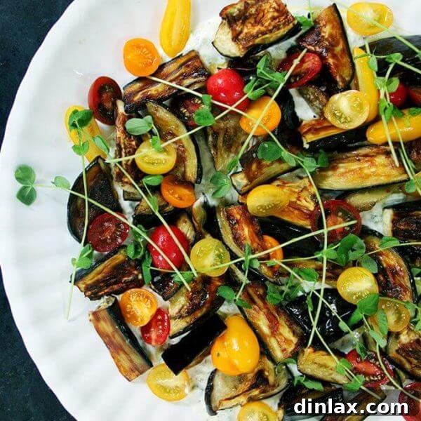Roasted eggplant salad on a platter with tzatziki and tomatoes.