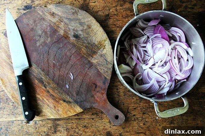 Marcella Hazan's Effortless Butter and Onion Tomato Sauce 6 A board aside a pot with melted butter and 2 sliced onions, slowly cooking.