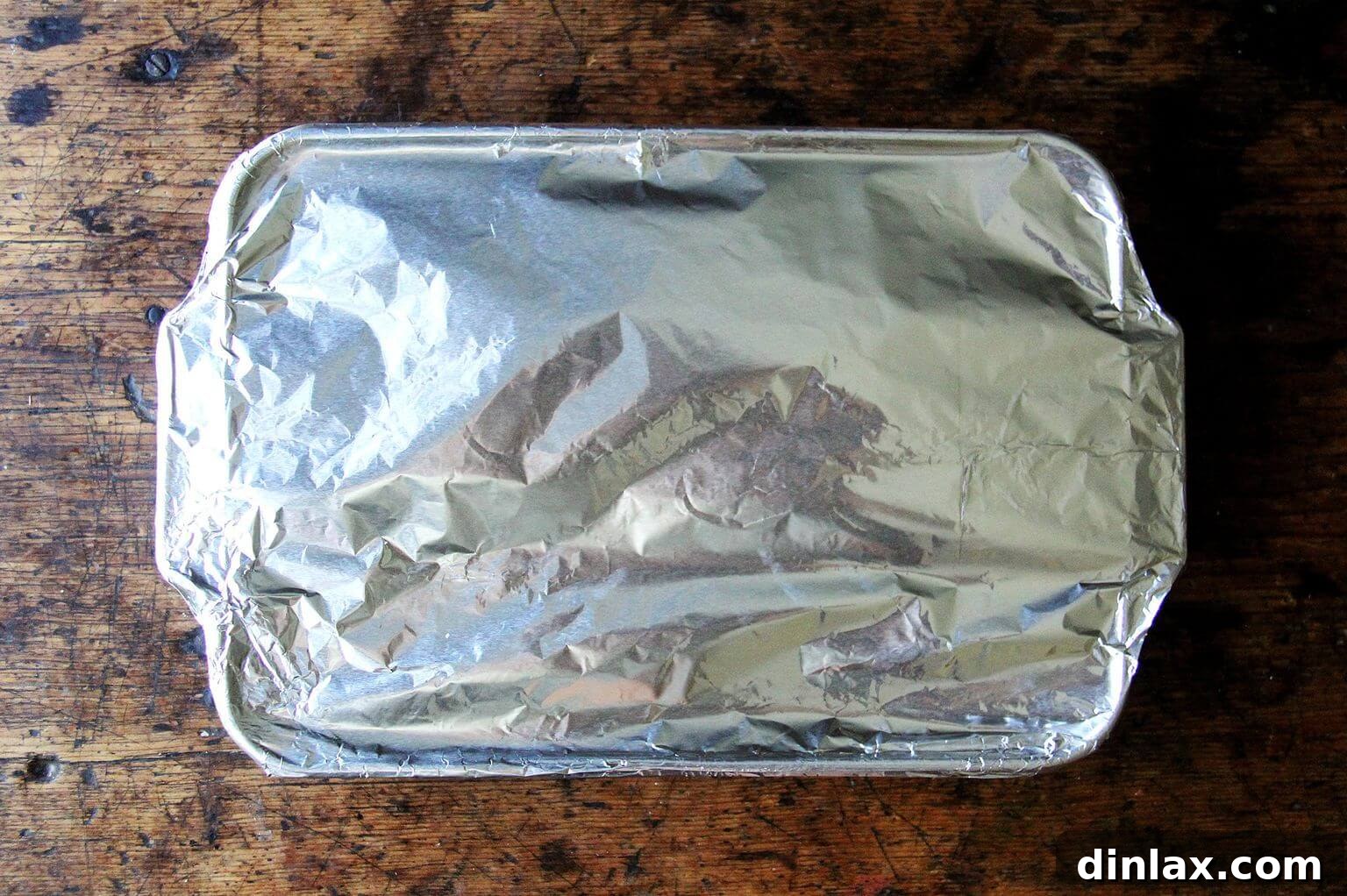 A 9x13-inch pan of unbaked lasagna covered in foil, ready for baking or storage.