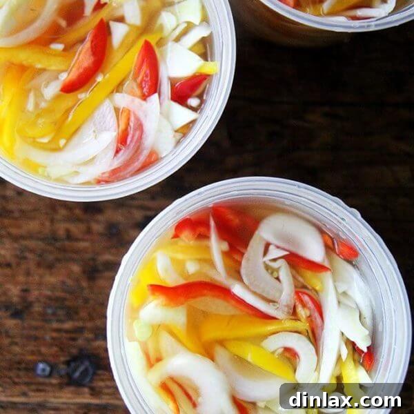 Close-up of vibrant pickled peppers, onions, and fennel in a jar, showcasing the rich colors and textures.