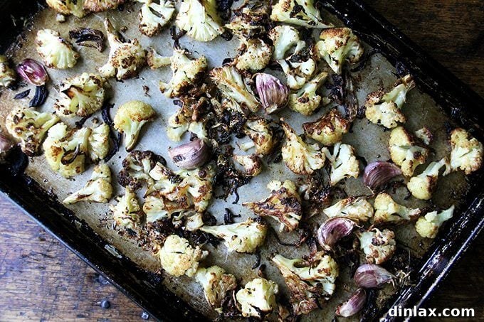 A glorious sheet pan of oven-roasted cauliflower florets, golden and tender, coated with crispy Parmesan cheese and intertwined with sweet, caramelized onions and soft roasted garlic.
