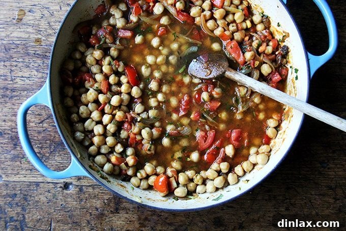 Sweet and Savory Chickpea Tagine with Tomato Jam and Roasted Delicata Squash 13 Water or chickpea cooking liquid poured into the braiser, covering the chickpeas, tomatoes, and spices before simmering.