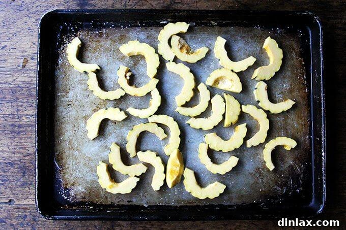 Sweet and Savory Chickpea Tagine with Tomato Jam and Roasted Delicata Squash 16 Uniformly sliced, raw delicata squash arranged on a sheet pan, ready for roasting.