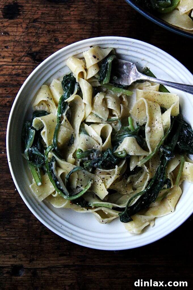 A beautifully presented plate of no-bacon carbonara, generously loaded with greens and topped with freshly cracked pepper, ready to be enjoyed.