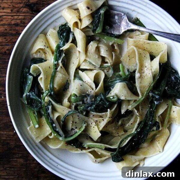 A bowl of creamy carbonara pasta with vibrant green vegetables.