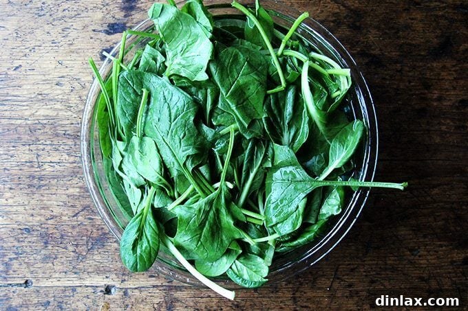 A bowl of fresh, leafy greens soaking in clear water, preparing them for cooking.