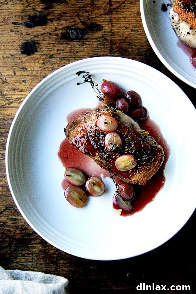 A plate of pan-seared Duck breasts with port wine sauce and roasted grapes, beautifully garnished with fresh thyme.
