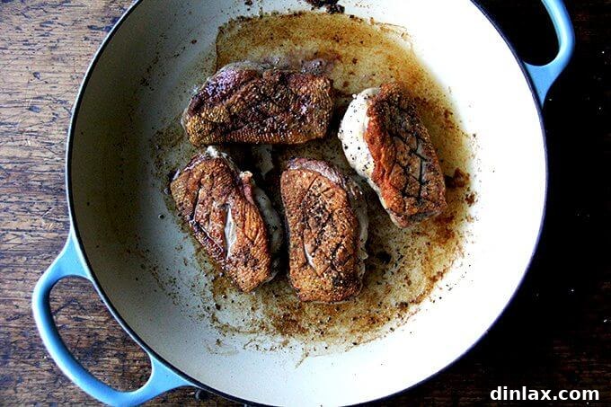 Four just cooked duck breasts resting in the Le Creuset braiser, ready to be transferred to a plate.