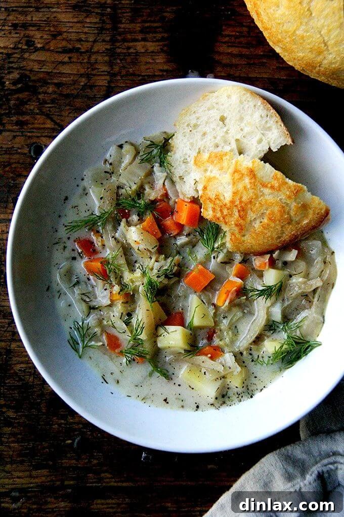 A vibrant bowl of vegetarian cabbage soup, garnished with fresh dill, served alongside crusty peasant bread.