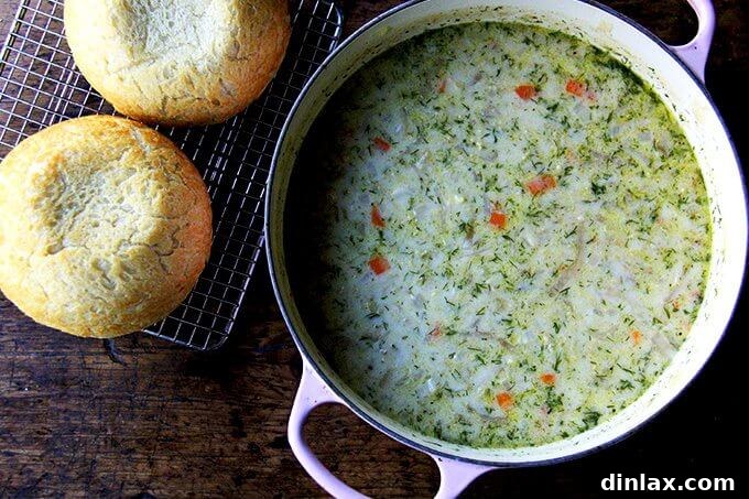 An overhead shot of a large pot of hearty vegetarian cabbage soup on a rustic wooden table, accompanied by two freshly baked loaves of homemade peasant bread, creating a perfect comfort meal.