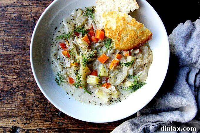 An overhead shot of a rustic bowl filled with hearty cabbage soup, garnished with fresh herbs, served alongside a slice of crusty bread, ready to be enjoyed.