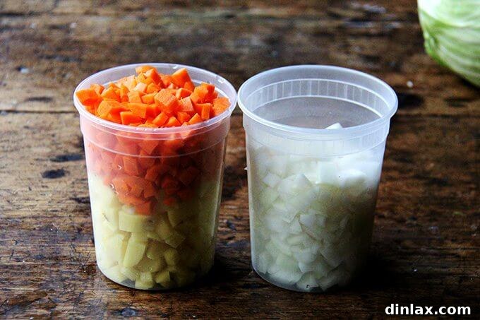 Two clear quart containers filled with neatly chopped vegetables: vibrant orange carrots, creamy white potatoes, and translucent yellow onions, prepped for a hearty soup.