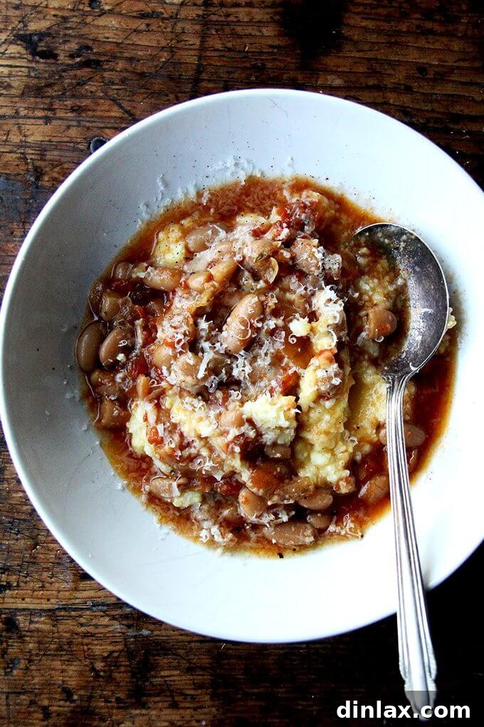 A generous bowl of slow-cooker gigante beans, rich in tomato and herb flavors, served alongside a comforting portion of golden oven-roasted polenta, creating a perfectly balanced meal.