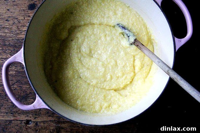 A Dutch oven, freshly removed from the oven, brimming with perfectly cooked, creamy oven-roasted polenta, showcasing its smooth and inviting texture.