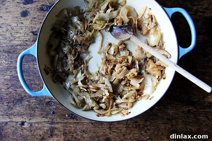 A braiser showcasing beautifully caramelized cabbage, rich in golden-brown hues and tender texture, having cooked down to a savory-sweet perfection.