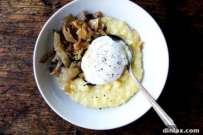 A rustic bowl filled with creamy polenta, topped with a generous portion of caramelized cabbage and a perfectly poached egg, awaiting enjoyment.