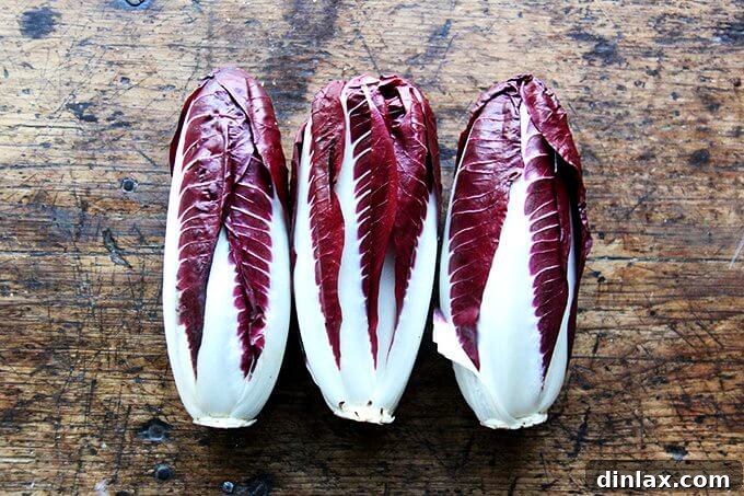 Close-up of freshly cooked penne pasta tossed with radicchio, walnuts, and a creamy Gorgonzola sauce, garnished with orange zest and parsley.