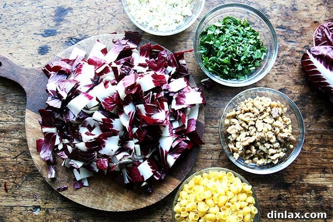 A close-up view of the ingredients for radicchio pasta, including fresh radicchio, walnuts, and a block of Gorgonzola cheese.