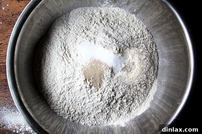 A bowl containing a mixture of flour, salt, and yeast, the dry ingredients for peasant bread.