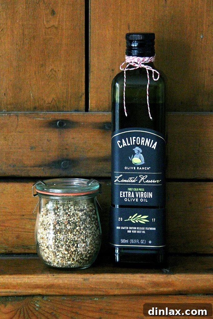 Crunchy Nut-Free Dukkah Blend 10 A bottle of California Olive Ranch extra virgin olive oil next to a jar of homemade nut-free dukkah, highlighting quality ingredients.
