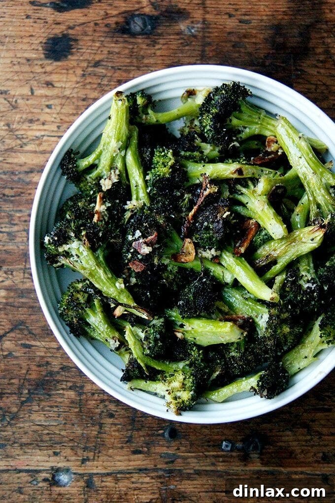 Ina Garten's Roasted Broccoli: A quick, easy, and utterly delicious side dish seasoned with fresh lemon zest, juice, and grated Parmesan, making it truly irresistible for any meal. Discover the magic of simple ingredients transformed into a year-round favorite. // alexandracooks.com A beautifully arranged bowl of Ina Garten's roasted broccoli florets, glistening with garlic, lemon, and parmesan cheese, ready to be served.