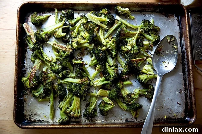 Ina Garten's Crispy Lemon Garlic Parmesan Roasted Broccoli 9 A sheet pan filled with beautifully roasted broccoli florets, perfectly tossed with freshly shaved Parmesan cheese and zesty lemon, creating an appetizing and vibrant side dish.