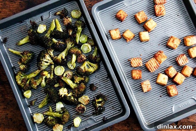 Golden Tofu and Broccoli with Savory Peanut Sesame Pesto 11 Roasted broccoli and crispy tofu cubes displayed on separate baking sheets, showcasing their golden-brown and charred textures after baking.