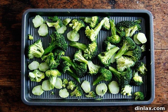 Golden Tofu and Broccoli with Savory Peanut Sesame Pesto 4 Broccoli florets and sliced stems spread in a single layer on a baking sheet, seasoned and ready to be roasted.