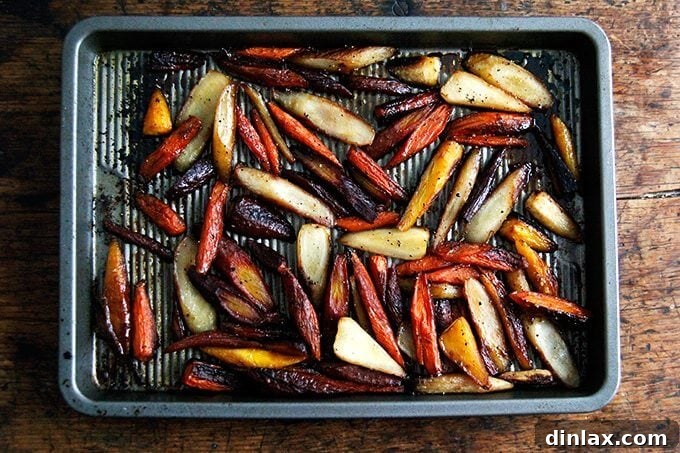 Twice-roasted carrots on a sheet pan, showing a beautiful caramelization and glistening glaze from the butter and honey.