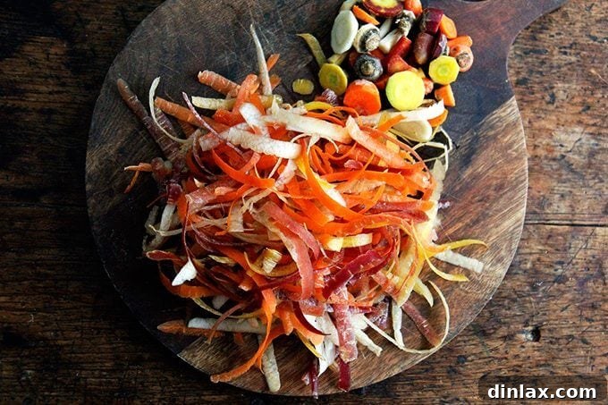 A close-up of carrot peels on a wooden cutting board, remnants of preparing fresh carrots for roasting.