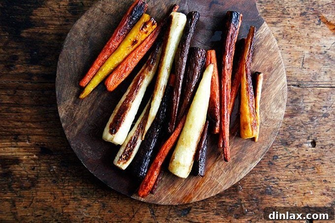 Roasted carrots on a sheet pan, showing distinct dark brown and slightly charred edges from their first high-heat roast.
