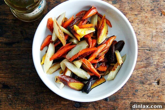 Sliced roasted carrots tossed with vinegar in a bowl, glistening and ready to absorb the tangy dressing.