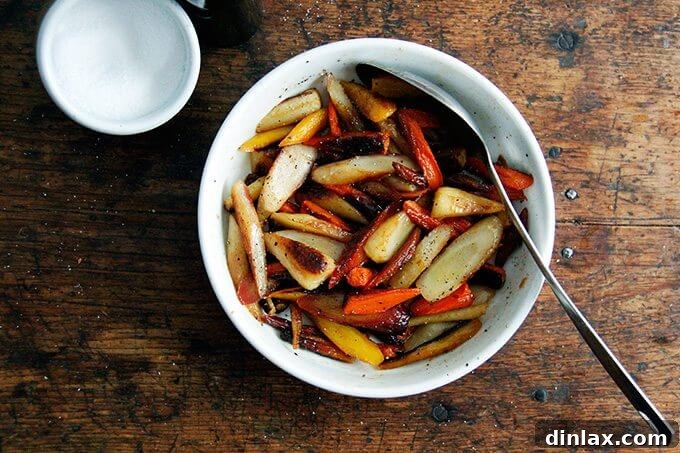 Roasted carrots in a bowl, generously seasoned with coarse salt and freshly ground black pepper.