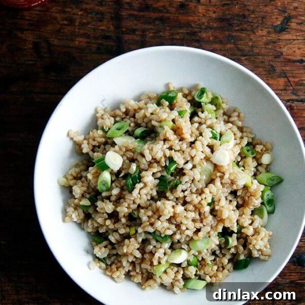 A bowl of perfectly cooked and seasoned Instant Pot brown rice, garnished with fresh scallions and sesame seeds.