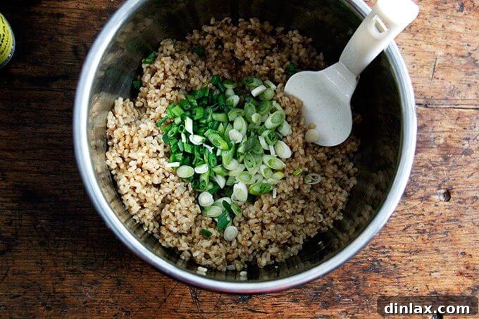 Your Ultimate Instant Pot Brown Rice: Perfect and Flavorful 10 An uncovered Instant Pot with perfectly cooked brown rice, now mixed with sliced scallions and ready for other seasonings.