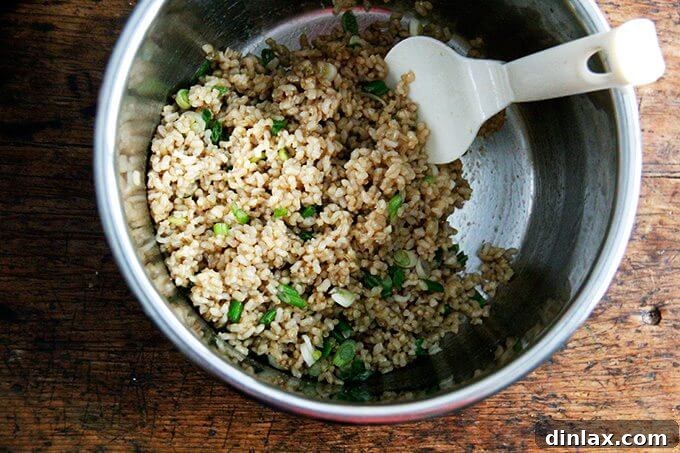 Your Ultimate Instant Pot Brown Rice: Perfect and Flavorful 11 An uncovered Instant Pot filled with perfectly cooked Instant Pot brown rice, scallions, and seasonings all tossed together, ready to serve.