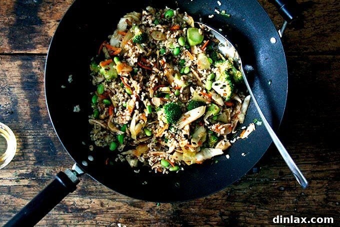 Cooked rice and green edamame are added to the wok, joining the mix of broccoli, shiitake, and kimchi, creating a colorful and robust base for the fried rice.