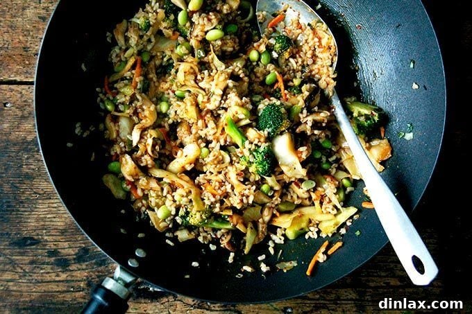 The kimchi fried rice is actively stir-frying in the wok, with all ingredients combined and heating through, creating an aromatic and visually appealing dish.