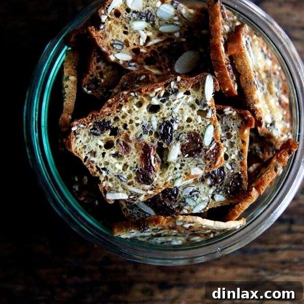 A jar brimming with golden-brown, homemade three-seed crackers, perfectly crisp and ready to be enjoyed.